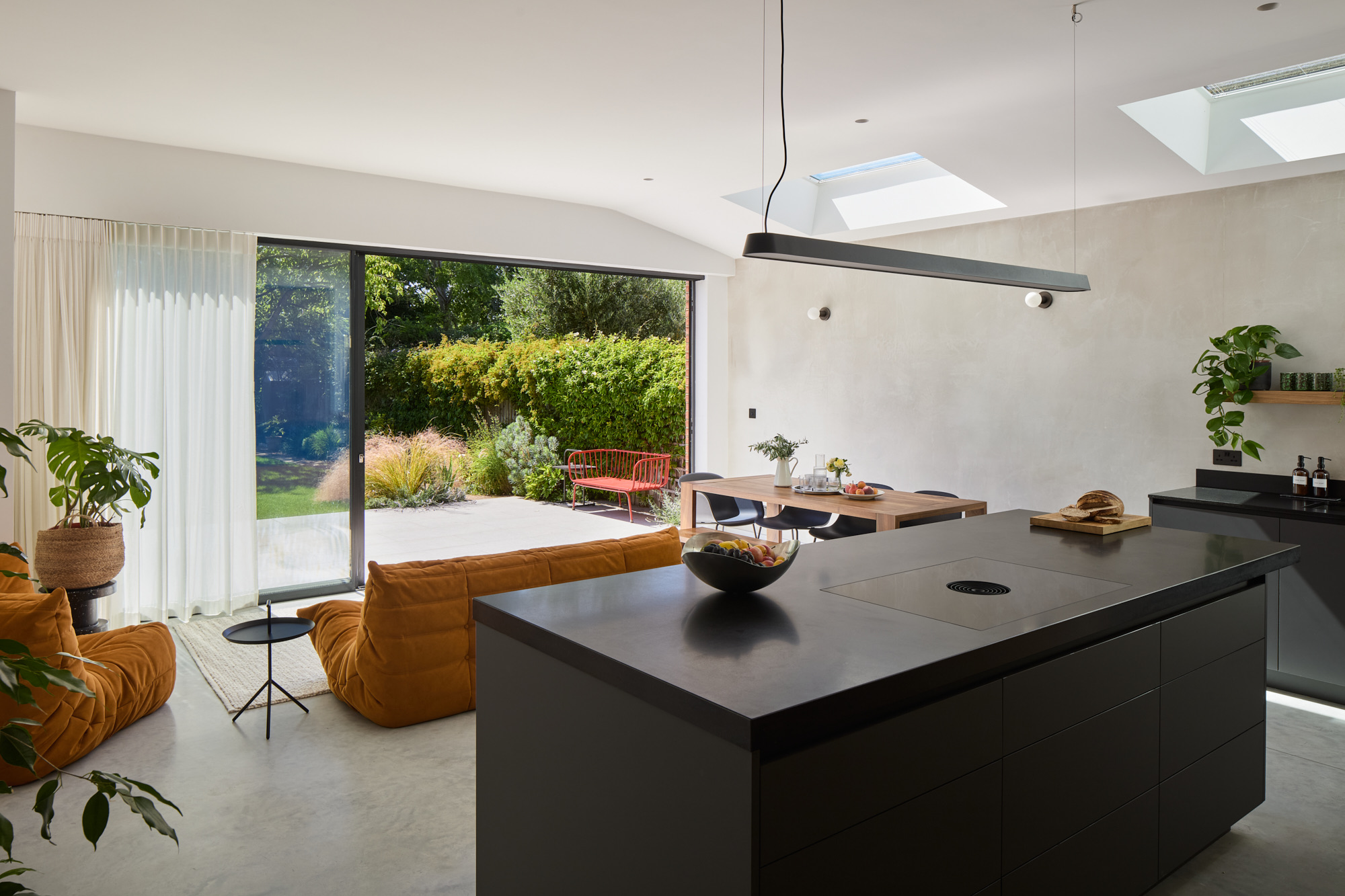 Modern open plan kitchen with polished concrete flooring and sliding doors to garden